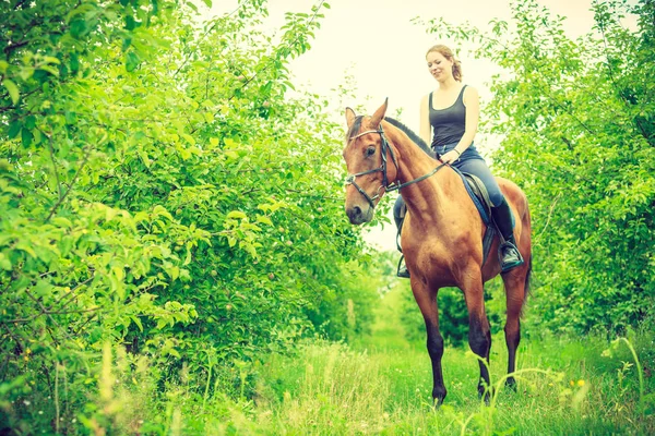 Jonge vrouw zitten op een paard — Stockfoto