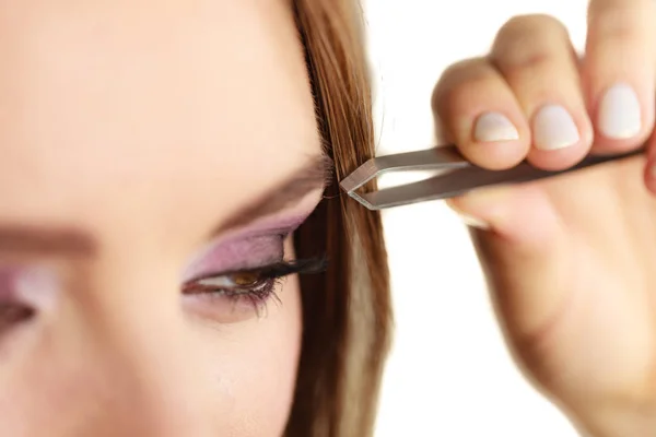 Woman tweezing eyebrows plucking with tweezers