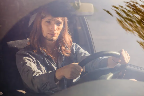 Giovane uomo con i capelli lunghi guida auto — Foto Stock