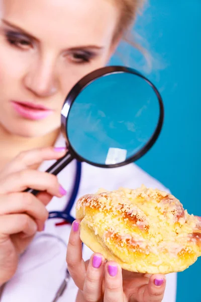 Doutor com lupa examinando alimentos doces — Fotografia de Stock