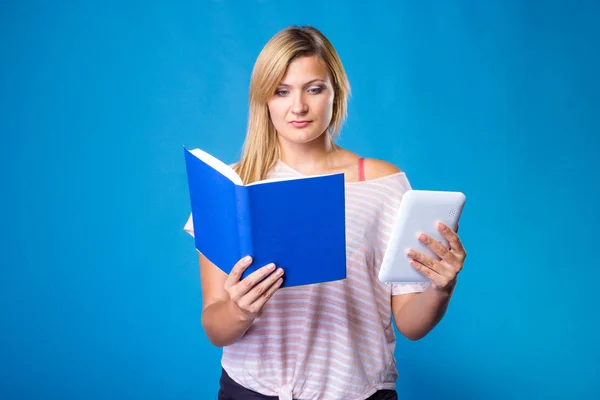 Blonde woman choosing between book and tablet — Stock Photo, Image