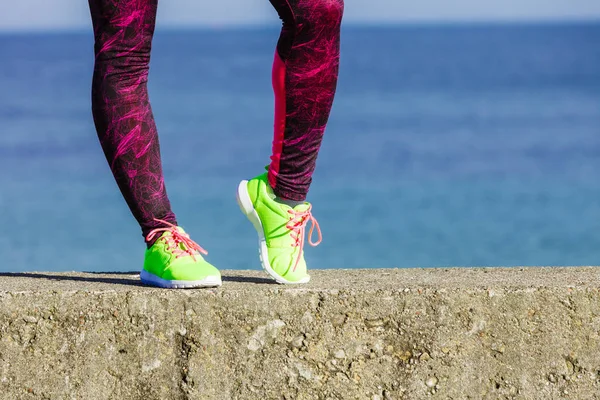 Jambes féminines pieds en couleur vive chaussures jaunes sur le bord de mer . — Photo