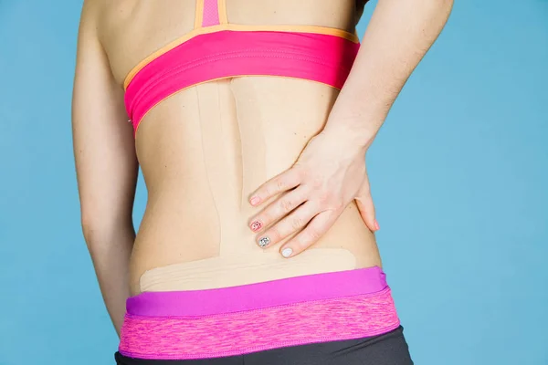 Kvinna med medicinsk kinesio taping på rygg — Stockfoto