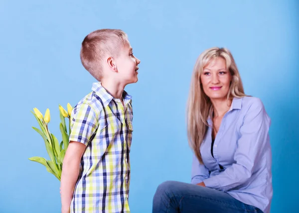 Menino com mãe segurar flores atrás das costas . — Fotografia de Stock