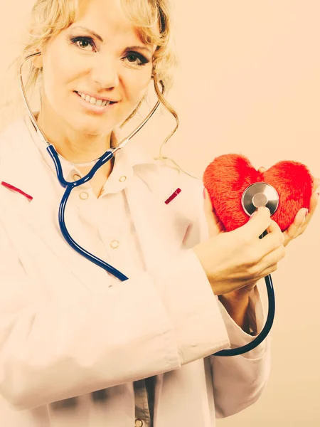 Médico con estetoscopio examinando el corazón rojo . — Foto de Stock