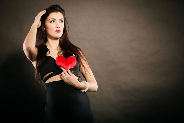 Schöne Frau hält rotes Herz auf schwarzem — Stockfoto