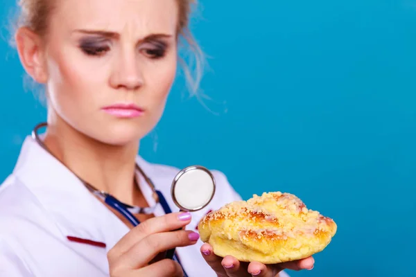 Diëtist onderzoeken zoete roll broodje met stethoscoop — Stockfoto