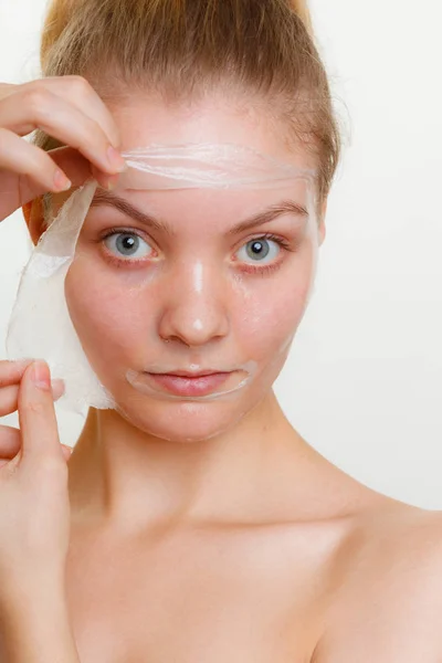 Frau entfernt Gesichtspeeling von Maske. — Stockfoto