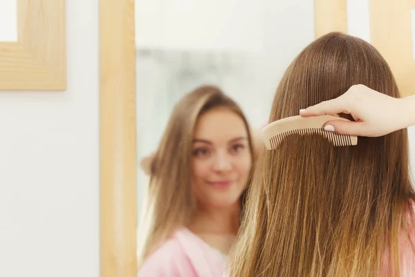 Mulher penteando seu cabelo comprido no banheiro — Fotografia de Stock