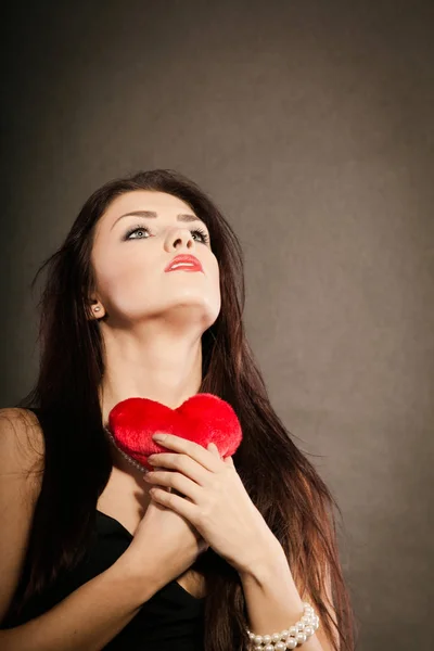 Mulher bonita detém coração vermelho no preto — Fotografia de Stock