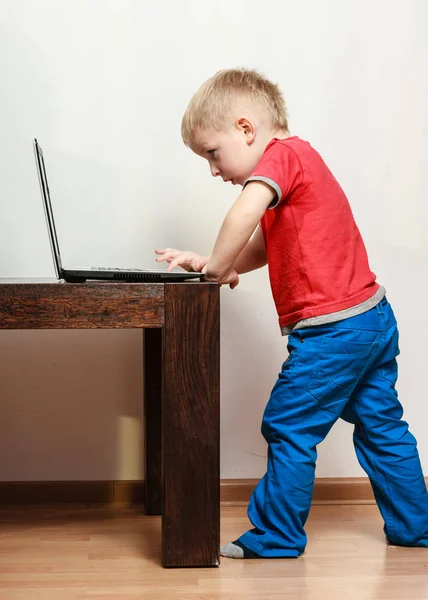 Petit garçon avec ordinateur portable sur la table à la maison . — Photo