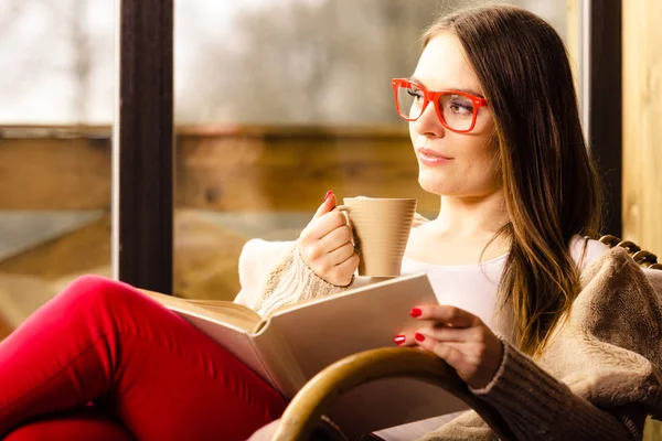 Mujer sentada en silla leyendo libro en casa —  Fotos de Stock