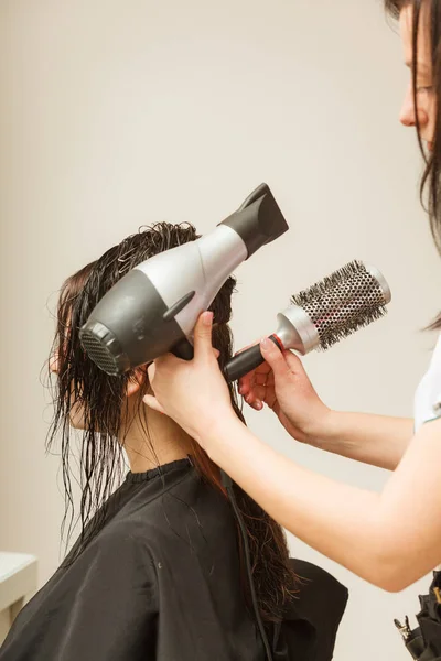 Hairdresser styling woman dark long hair — Stock Photo, Image