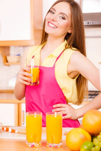 Mulher na cozinha beber suco de laranja fresco — Fotografia de Stock