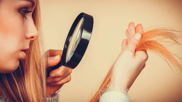 Traurige Frau blickt auf beschädigte Haarspitzen. — Stockfoto