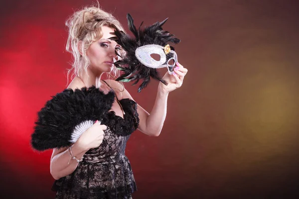Kvinnan håller carnival mask fjäder solfjäder i hand — Stockfoto