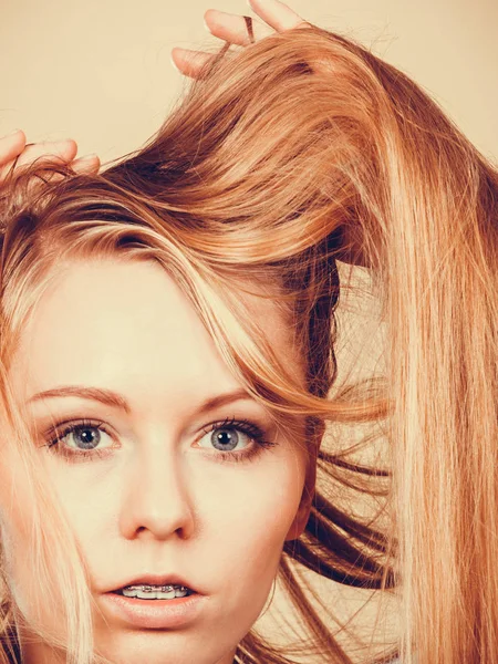 Mujer rubia sosteniendo su largo cabello enredado — Foto de Stock