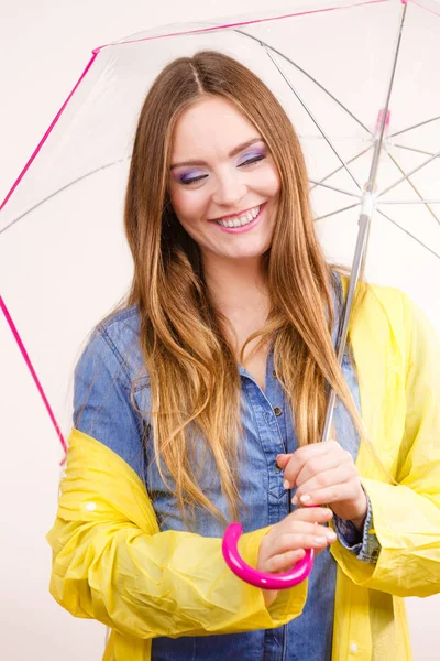 Frau trägt wasserdichten Mantel unter Regenschirm — Stockfoto