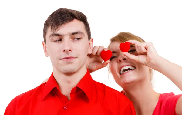 Serious man and crazy woman holds red hearts over eyes — Stock Photo, Image