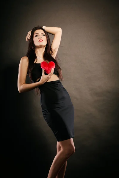 Mulher bonita detém coração vermelho no preto — Fotografia de Stock