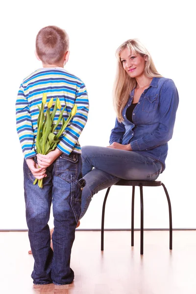 Niño pequeño con madre sostener flores detrás de la espalda . —  Fotos de Stock