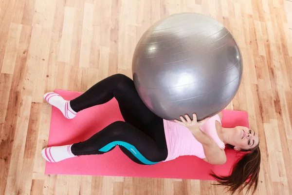 Mladá dáma leží na podložce s fit ball. — Stock fotografie