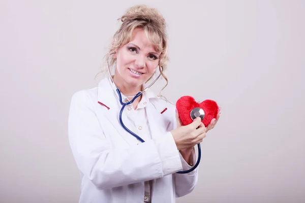 Médico com estetoscópio examinando coração vermelho . — Fotografia de Stock