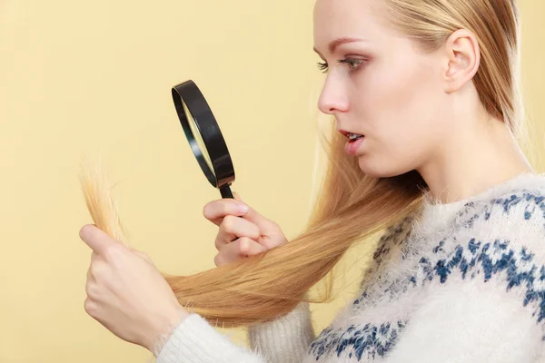 Treurige vrouw kijkt van beschadigd haar uiteinden. — Stockfoto