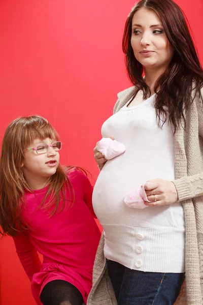 Donna incinta con bambina in possesso di scarpe per bambini — Foto Stock
