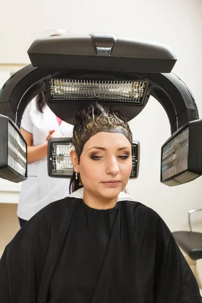 Donna in parrucchiere, asciugatura capelli sotto macchina — Foto Stock