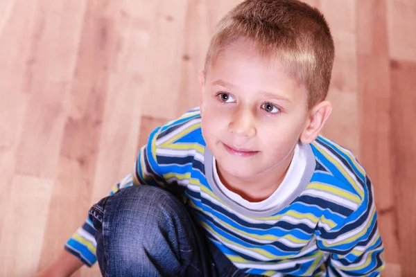 Jonge jongen zitten op houten vloer en glimlach. — Stockfoto