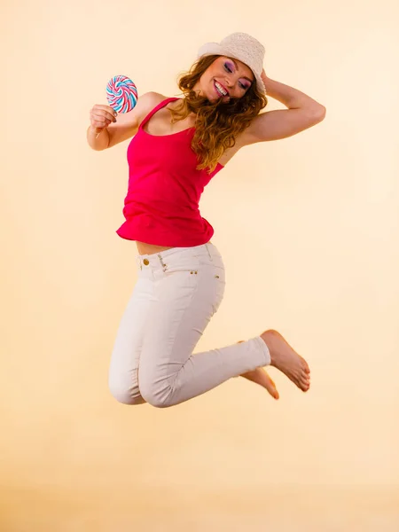 Positive woman jumping holds lollipop candy in hand — Stock Photo, Image