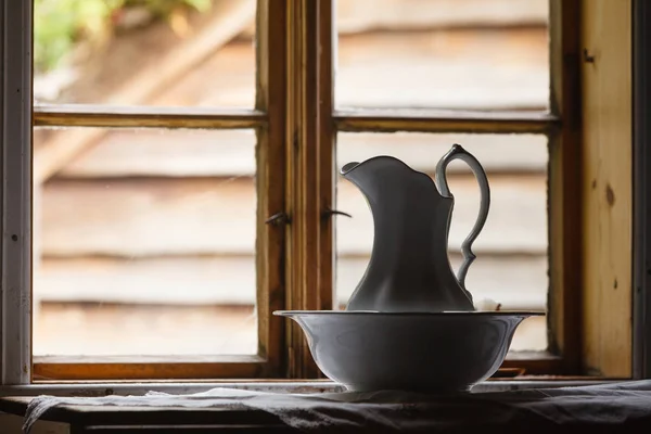 Old vintage window, ceramic jug in foreground — Stock Photo, Image