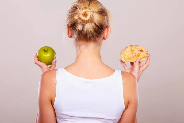 Femme tient gâteau et fruits à la main en choisissant — Photo