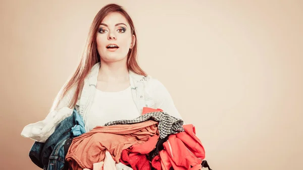 Junge Frau hält Stapel Kleidungsstücke. — Stockfoto