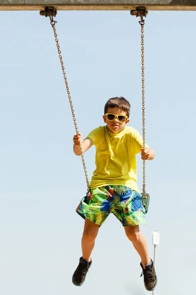 Boy playing swinging by swing-set. — Stock Photo, Image