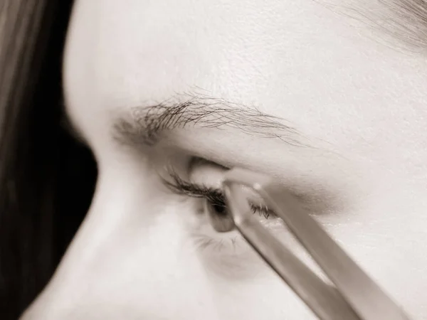 Woman tweezing eyebrows depilating with tweezers — Stock Photo, Image