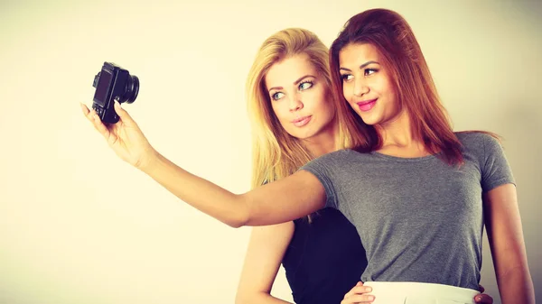 Twee modellen meisjes nemen zelf foto met camera — Stockfoto