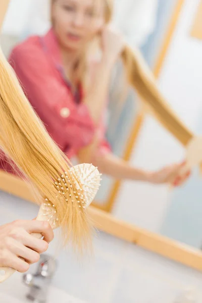 Mulher escovando seu cabelo longo no banheiro — Fotografia de Stock