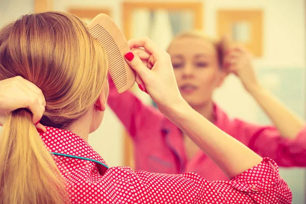 Woman combing her long hair in bathroom — Stock Photo, Image