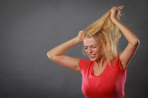 Frustrada mulher segurando seu cabelo loiro danificado — Fotografia de Stock