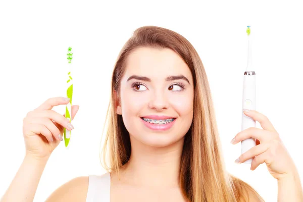 Mujer con tirantes sosteniendo cepillo de dientes eléctrico y tradicional —  Fotos de Stock