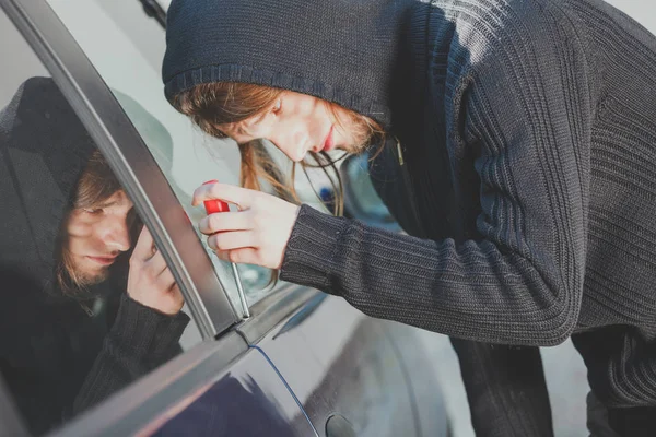Thieft man holding screwdriver breaking into car — Stock Photo, Image