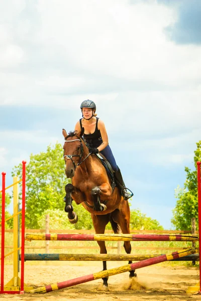 Cavalo De Baía Com Garota De Jóquei Pulando Sobre Um Obstáculo. Um