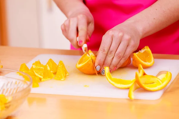 Femme au foyer dans la cuisine coupe des fruits orange — Photo