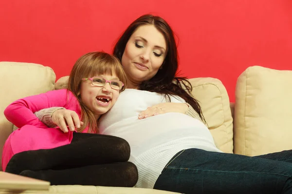 Pregnant woman sitting on sofa with daughter — Stock Photo, Image