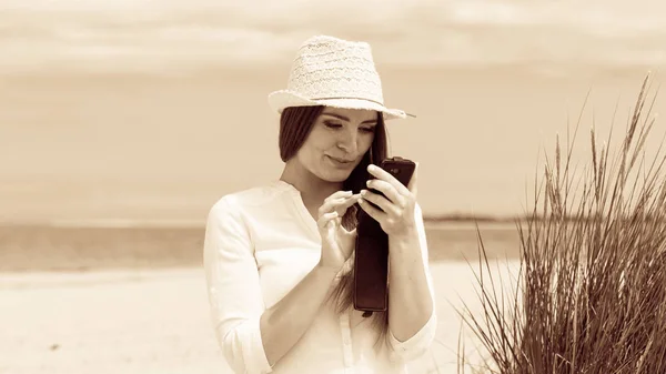 Женщина на пляже пишет смс на смартфоне . — стоковое фото