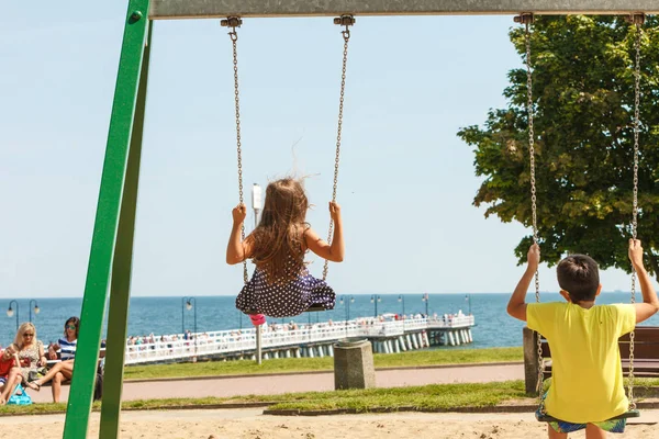 Two children having fun on swingset. — Stock Photo, Image