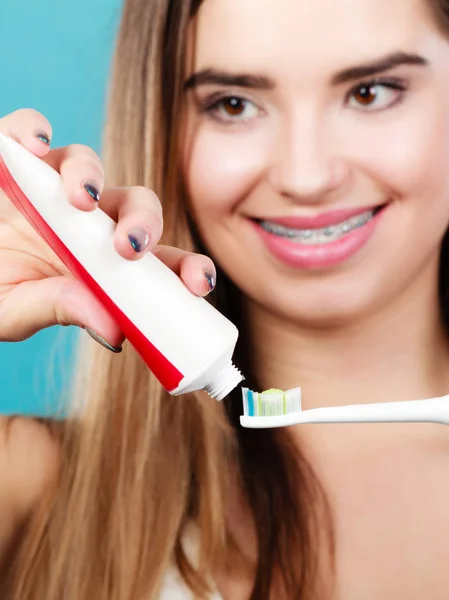 Mujer con frenos sosteniendo cepillo de dientes y pasta de dientes —  Fotos de Stock