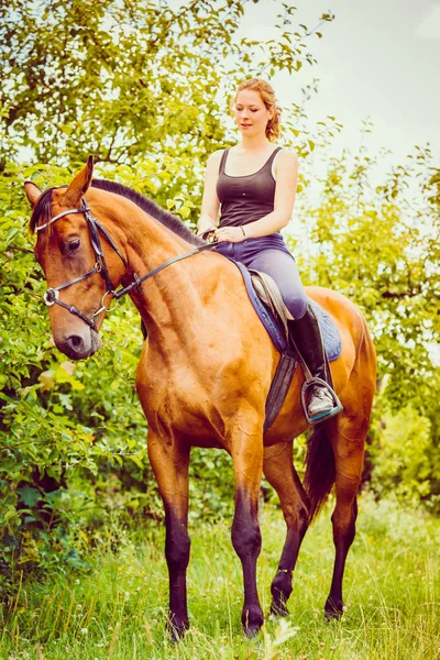 Ung kvinna sitter på en häst — Stockfoto